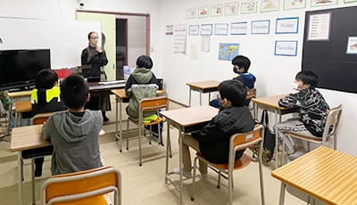 英会話教室で小学生に座学で英語を教える外国籍教師